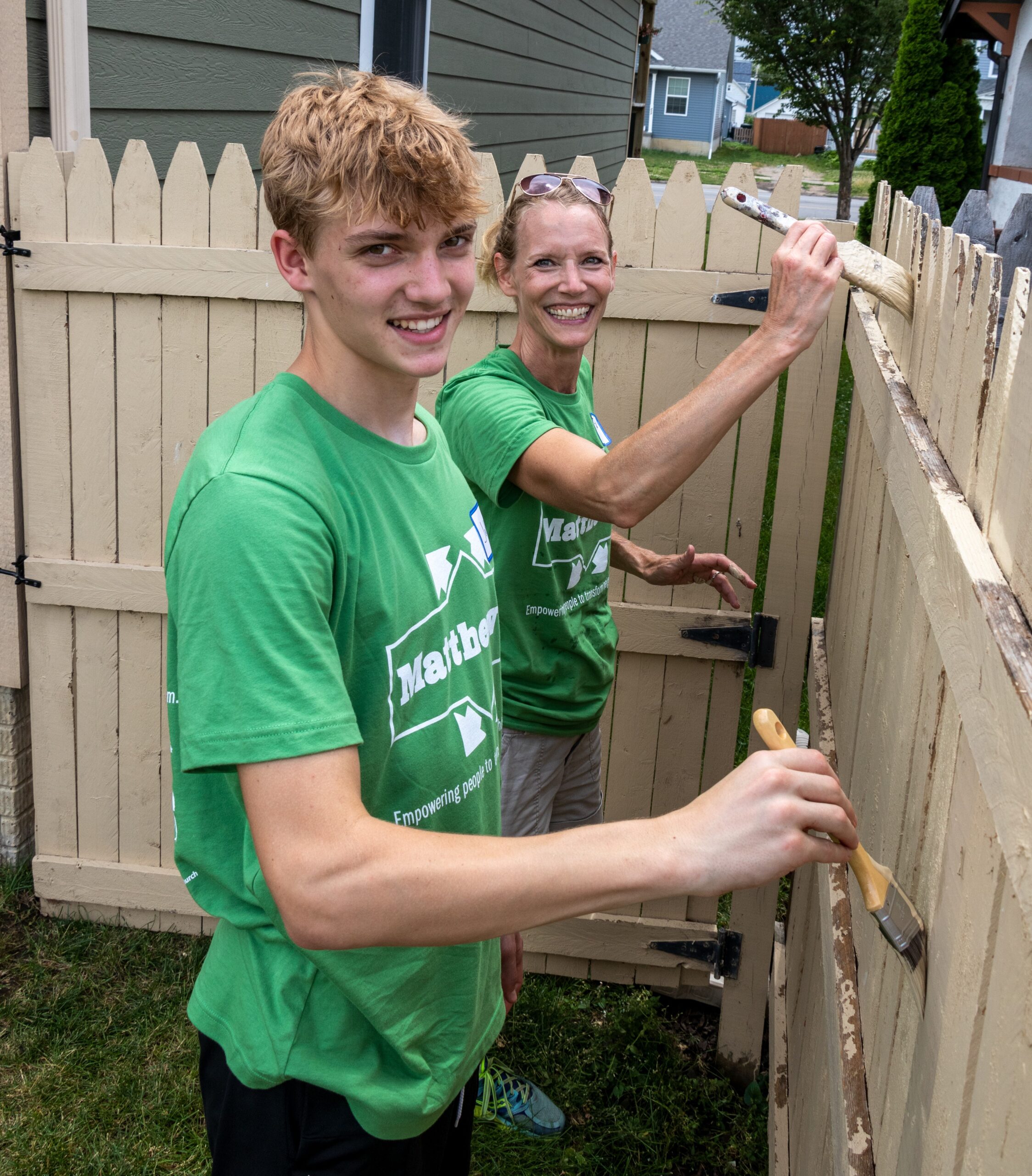 volunteers painting a brown fence
