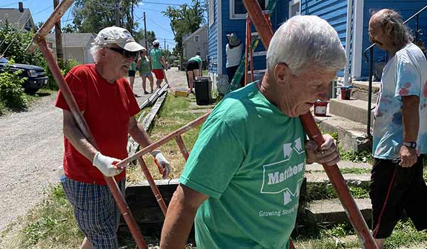 Two volunteers carry items to help improve a home