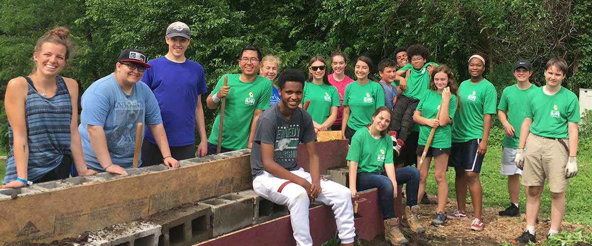 A group of students pose in green shirts